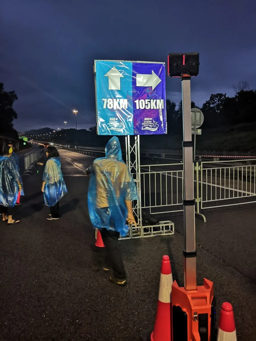 Battery tower light beside night route direction signage and cones